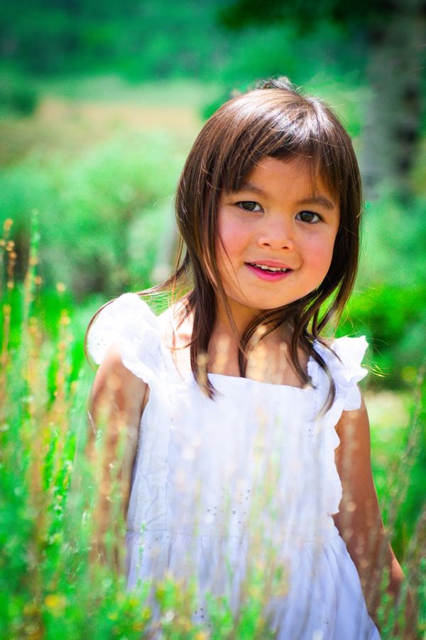 Young girl in a white dress surrounded by greenery