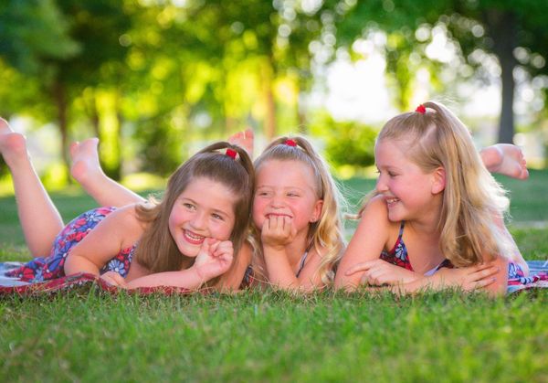 Three young girls lying together in the grass