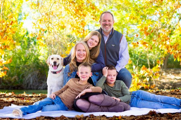 Family of six with their dog among fall leaves